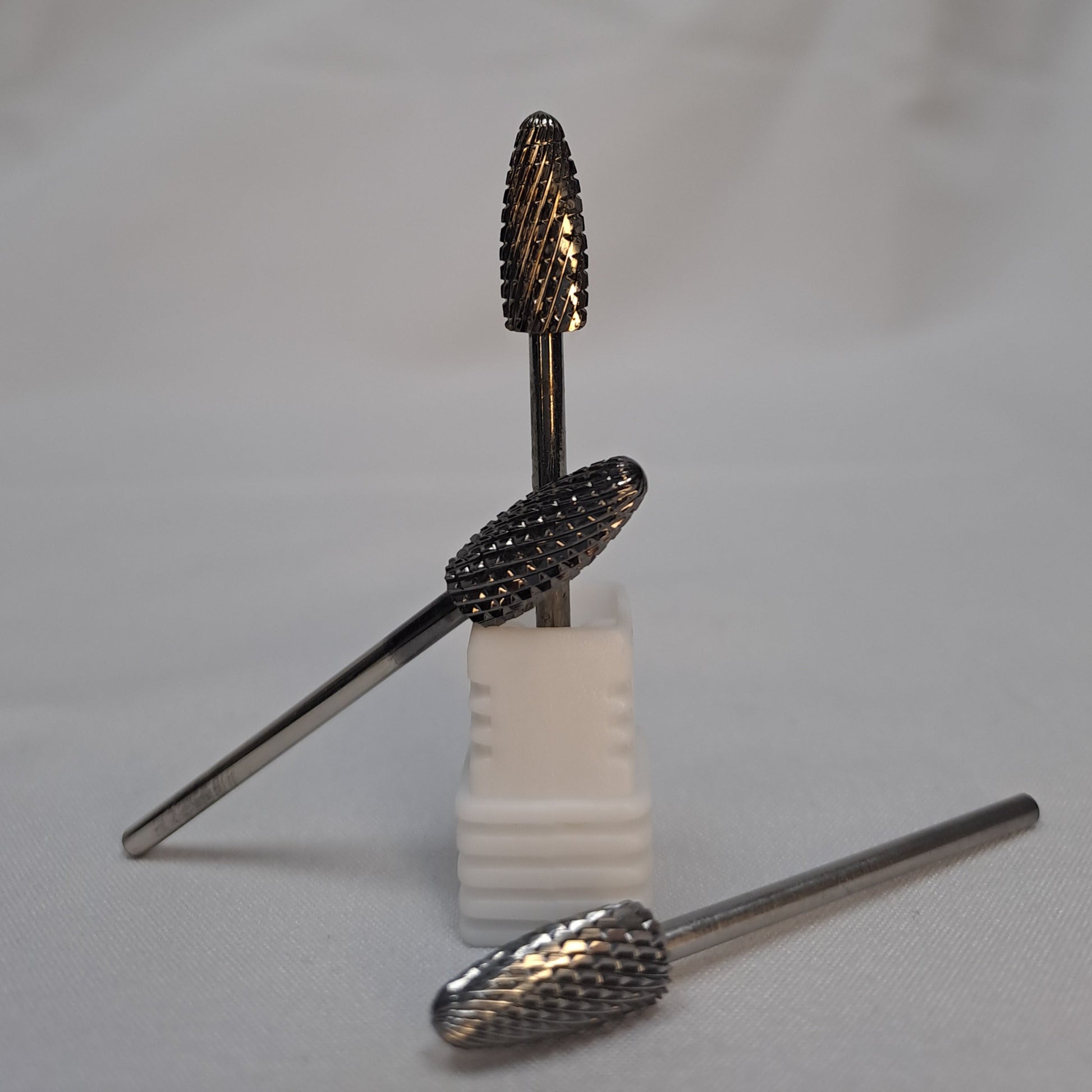 Nail drill bit on a white block with a plain background